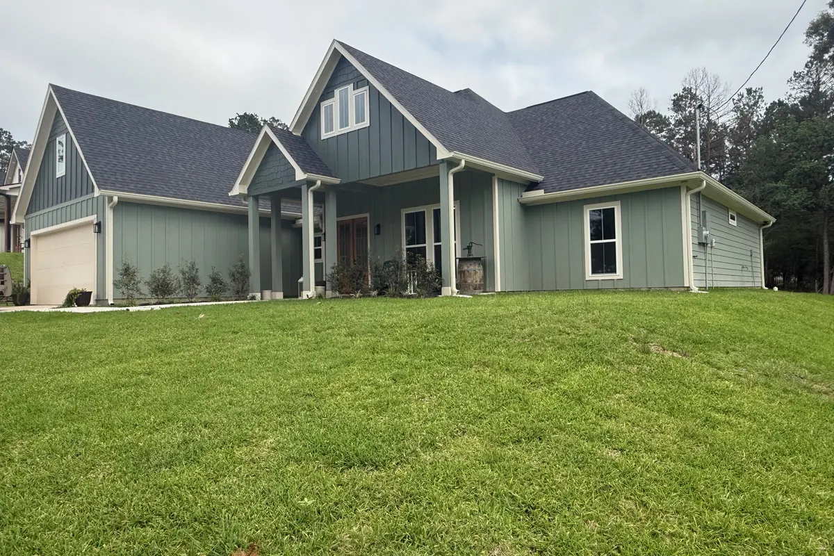 Finished home with light green board-and-batten siding, white seamless gutters, and downspouts