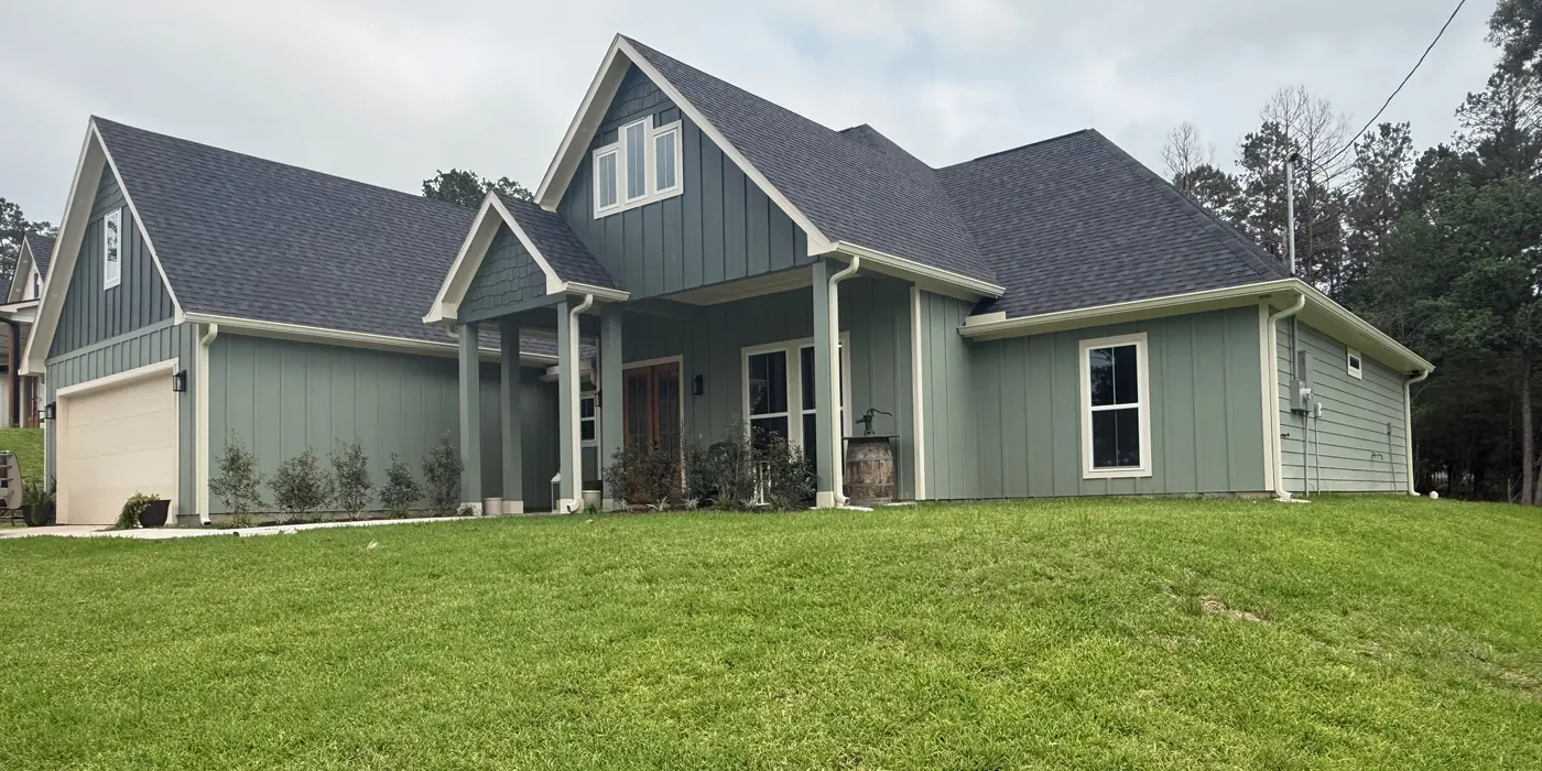 Finished home with light green board-and-batten siding, white seamless gutters, and downspouts